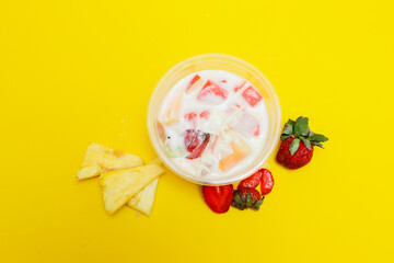 es buah or sup buah is indonesian fruit cocktail ice desert, contains strawberry, pineapple, and other tropical fruits mixed with ice cube, and condensed milk. isolated on yellow background.