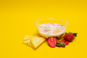 es buah or sup buah is indonesian fruit cocktail ice desert, contains strawberry, pineapple, and other tropical fruits mixed with ice cube, and condensed milk. isolated on yellow background.