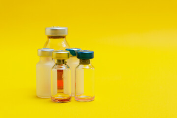 photo of several vials of injection medicine isolated on yellow background