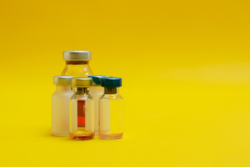 photo of several vials of injection medicine isolated on yellow background