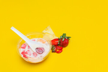 es buah or sup buah is indonesian fruit cocktail ice desert, contains strawberry, pineapple, and other tropical fruits mixed with ice cube, and condensed milk. isolated on yellow background.