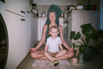 Modern yogini mom meditates while toddler sits on her lap. Morning routine of working mother.