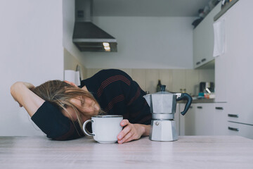 Tired sleepy person female having some problems. Exhausted woman with coffee at home. Сoncept of woman or mother in depression, burnt out, tired from work or study, unsatisfactory with life.
