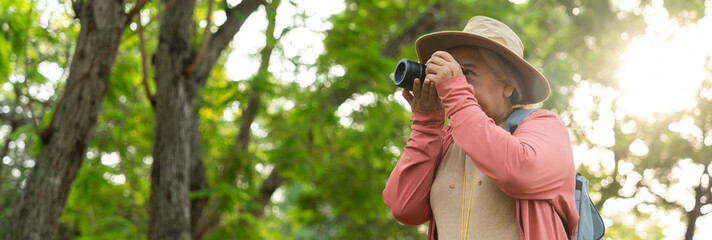 Portrait of Asian mature woman holding a camera and backpack behind her back, an Asia active senior...