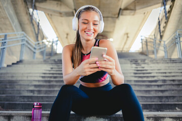 Young fit Caucasian woman using her cellular phone before starting her workout.