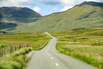 Visit Ireland: Road running in winding curves into a valley in Ireland's county Connemara near...