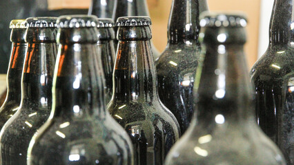 Dusty old beer bottles in a forgotten corner of a storehouse - obrazy, fototapety, plakaty