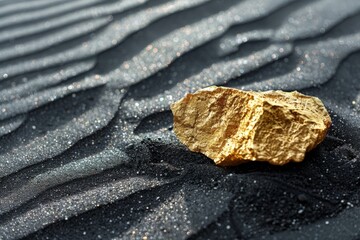 A gold rock is sitting on a black sand beach