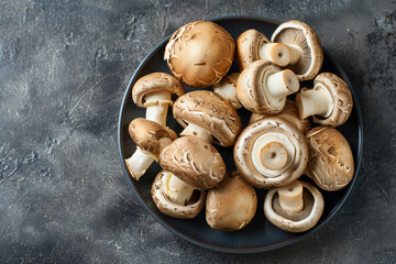 Top view of raw mushrooms on dark plate, ideal for culinary themes and healthy eating blogs.