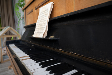 Fototapeta na wymiar black old piano in cracks with notes