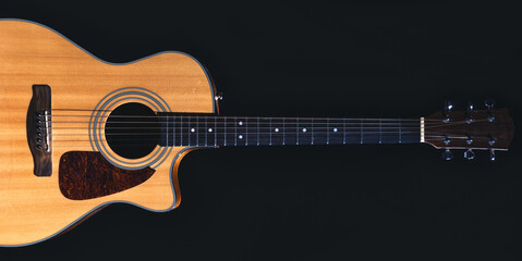 Acoustic guitar on a black background, flat lay.