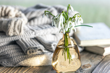 A bouquet of snowdrops in a glass vase on a blurred background.