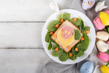 Creative homemade Easter sandwiches for kids breakfast. Funny sandwiches in form of Easter symbols - sheep, chicken, bunny, made with toasted bread, cheese, sausages, spinach and carrot
