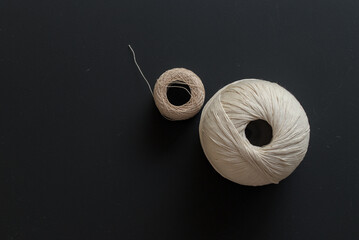 pair of balls of cotton thread on black background