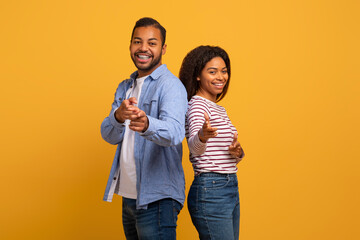 Cheerful young black couple playfully pointing at the camera with confident smiles