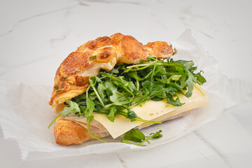 Turkey and cheese sandwich on a jalapeno croissant topped with escorole