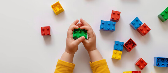 The hand kid is holding a brick box of Lego on a white background - obrazy, fototapety, plakaty