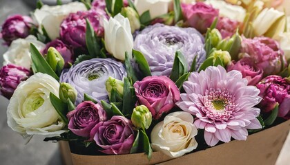 many beautiful flower mono bouquets of fresh roses ranunculus lilac matthiola tulips wrapped in paper placed in a cardboard transportation box close up view