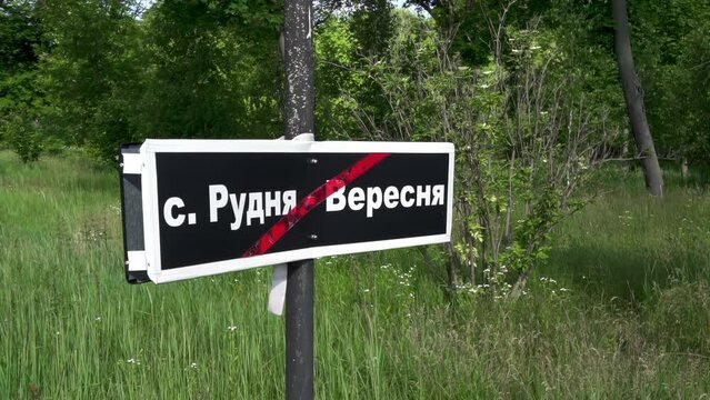 Chernobyl sign. The name of the destroyed village "Rudnia-Veresnya" is written in white letters on a black plaque. The Chernobyl tragedy: Disappeared villages.