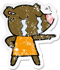 distressed sticker of a cartoon crying bear in dress pointing
