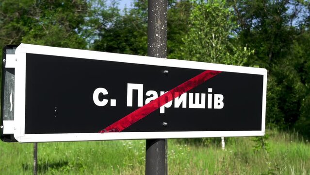 The Chernobyl Exclusion Zone: Abandoned, destroyed villages. The name of the destroyed village of Paryshiv is written in white letters on a black board.