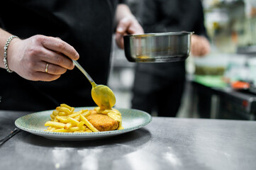 chef cooking Fried Wiener schnitzel from veal topside with French fries and cheese sauce on kitchen