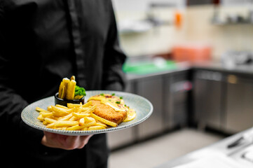 chef cooking Fried Wiener schnitzel from veal topside with French fries and cheese sauce on kitchen