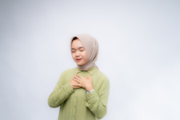 Happy mindful thankful young Asian Muslim woman with her hand on her chest smiling isolated on...