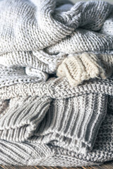 Knitted warm grey sweaters. Cozy composition in the home atmosphere.