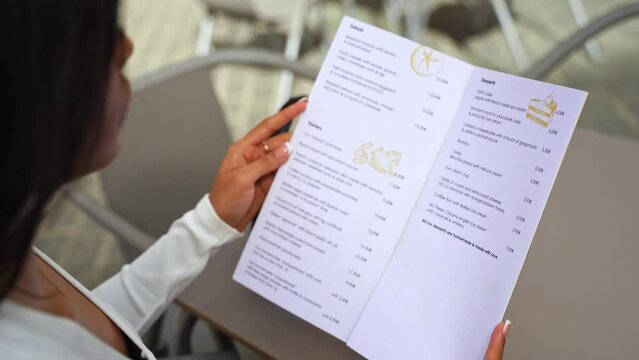 Close-up hands of Elegant Woman Hold Menu Restaurant Choosing Dish or Beverage Lunch City Break. Eating in Public Places Cafeteria. Ordering for waiter. Slim Woman Diet Catering Alcohol Drink Dish.