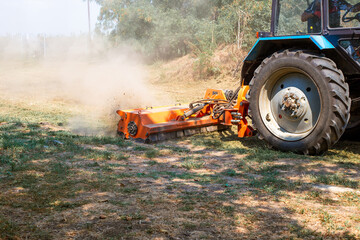 A tractor with a mulcher crushes and levels the top layer of soil. Agricultural work