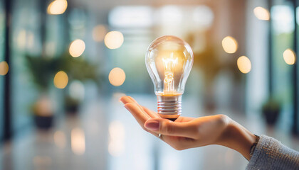 female hand holding blurred light bulb in bright interior. Symbolizing ideas, creativity, inspiration