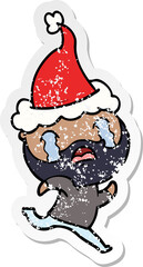 distressed sticker cartoon of a bearded man crying wearing santa hat