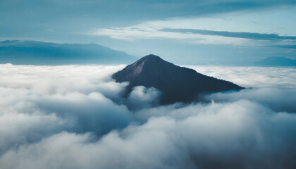 Majestic lone mountain peak emerges above clouds, evoking solitude and awe in cool, serene tones