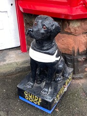 Porlock, Somerset, UK: 12.02.2024 - guide dogs for blind charity donation collection box  statue...