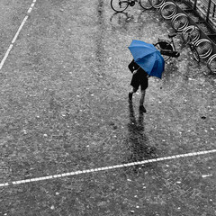 Uomo che passeggia sotto la pioggia con ombrello colorato in un ambiente bianco e nero
