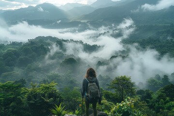 Adventurous hike through lush forest, Individual stands on a mountain peak, surveying the fog-draped valleys below, embodying the grandeur of the highlands and the serenity of the morning light.
