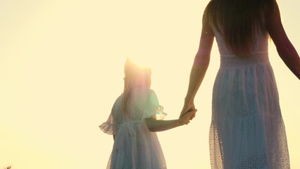 Family mother and daughter walking outdoor bright sun sky nature landscape enjoy freedom closeup back view. Elegant woman and girl kid in white dress going holding hands at sunlight sunset sunrise