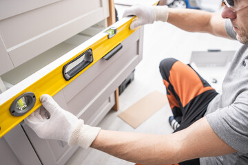 Cabinetmaker Fitting Kitchen Furniture Drawer and Checking Levels