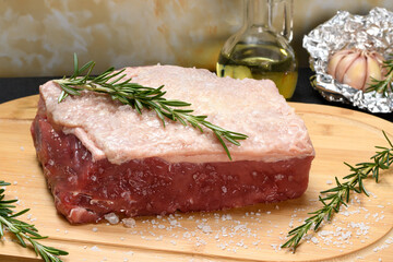 RAW BEEF FILLET WITH SALT AND ROSEMARY ON A CUTTING BOARD