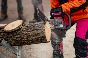 Chainsawing wooden log with battery powered chain saw tool