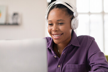 Smiling black female teen student with headphones at computer