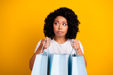Photo of upset disappointed woman dressed white t-shirt hold new outfit in bags look empty space...