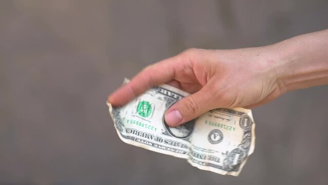 A crumpled 1 dollar bill in hand