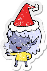 happy distressed sticker cartoon of a elf girl pointing wearing santa hat