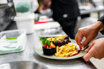 chef hand cooking Pork ribs with french fries and sauce on kitchen