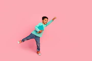 Full size photo of charming small boy hold books flying superhero wear trendy aquamarine outfit isolated on pink color background