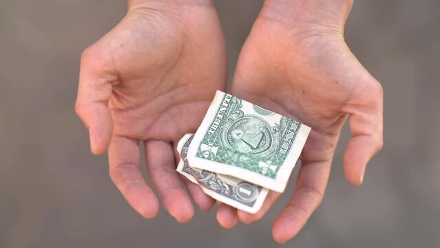 A $1 bill falls into open palms.