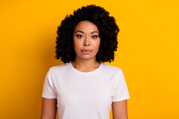 Photo of serious confident woman with perming coiffure dressed white t-shirt look at you isolated on vibrant yellow color background