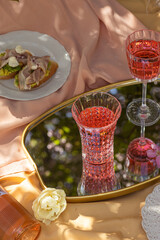 Closeup glass of rose wine , picnic basket, food and flowers on the spring blossom garden. Banner